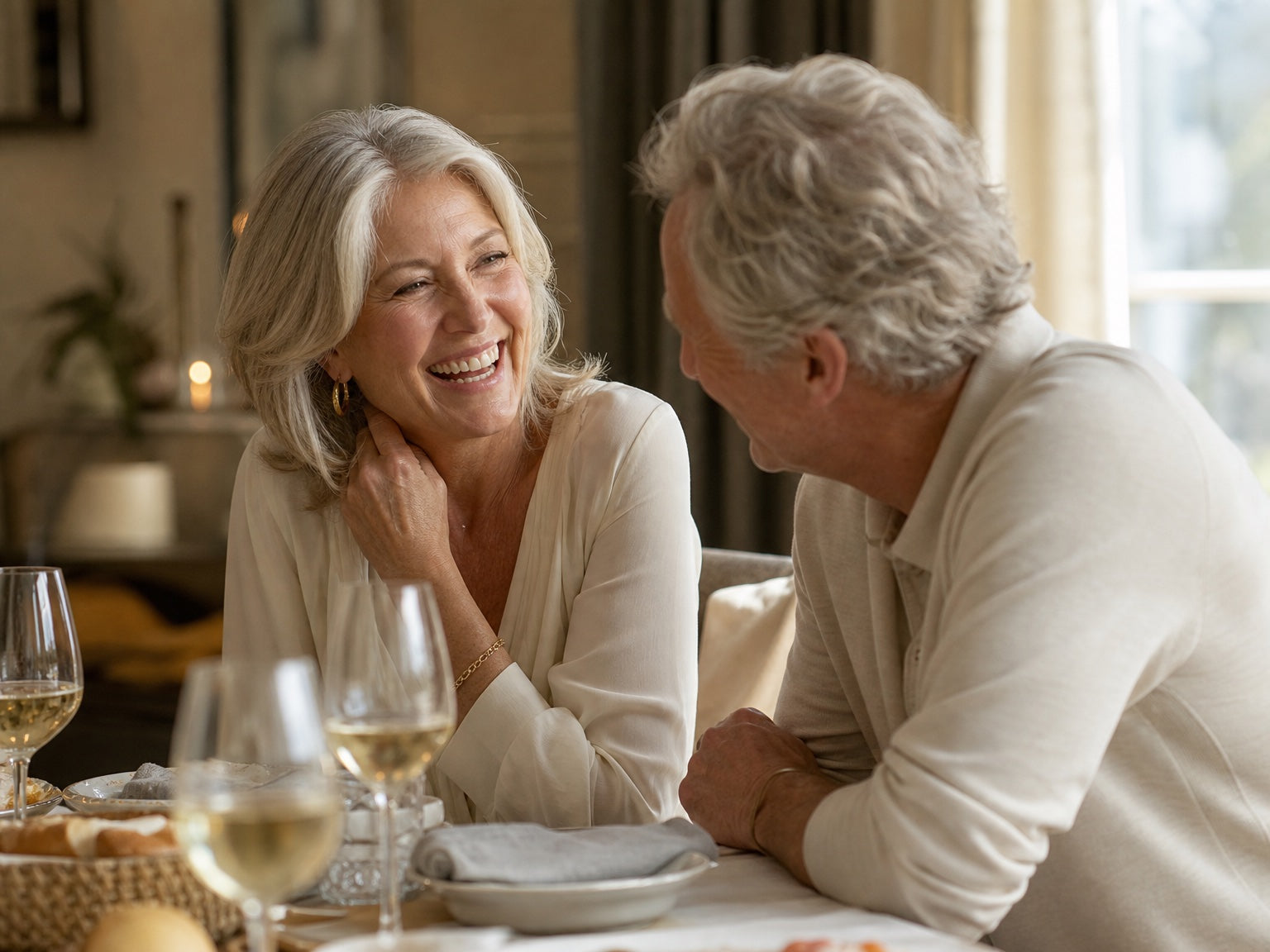 A man leaning in toward a laughing woman at a dinner table