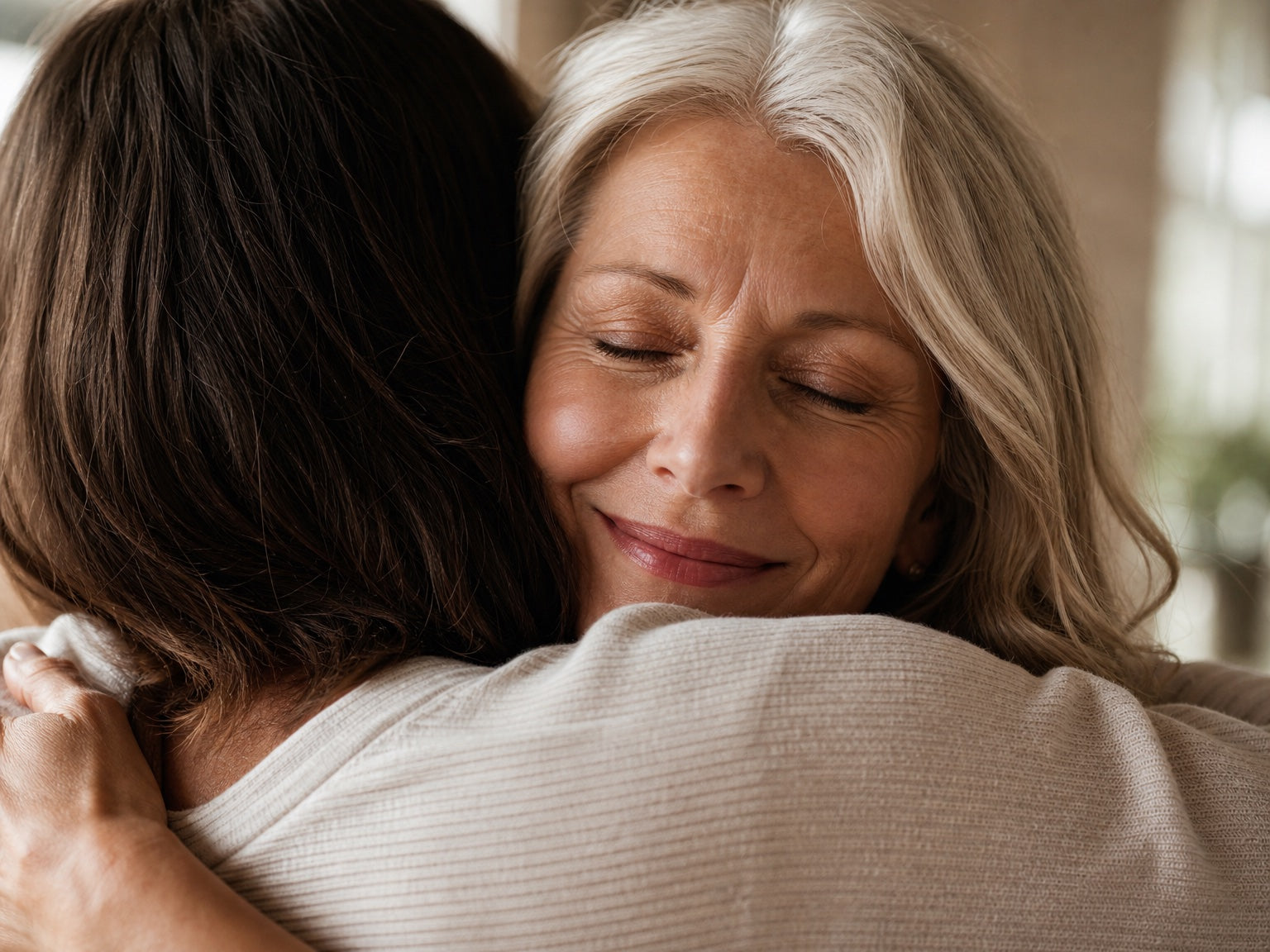 A woman held in a close hug, eyes softly closed